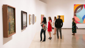 small crowd in a gallery looking at paintings