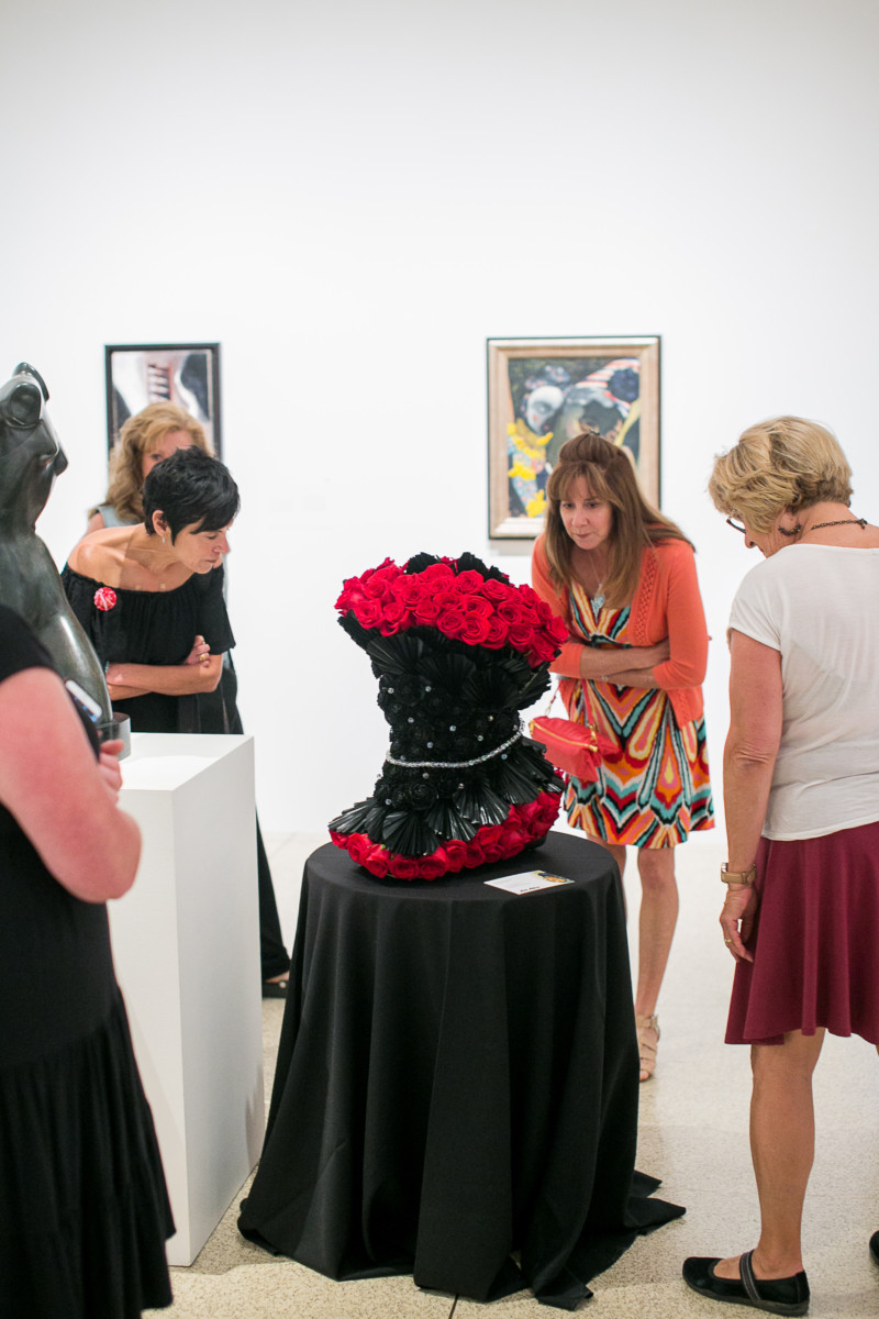 group of women looking at floral arrangement in art museum gallery