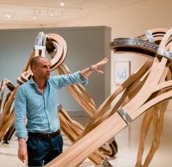 man explaining something in room of sculptures
