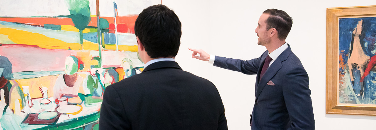 Two men looking at paintings in a gallery