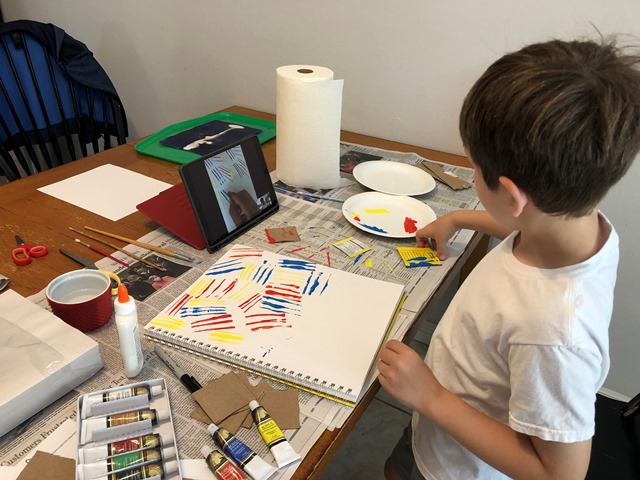 boy painting at table with ipad