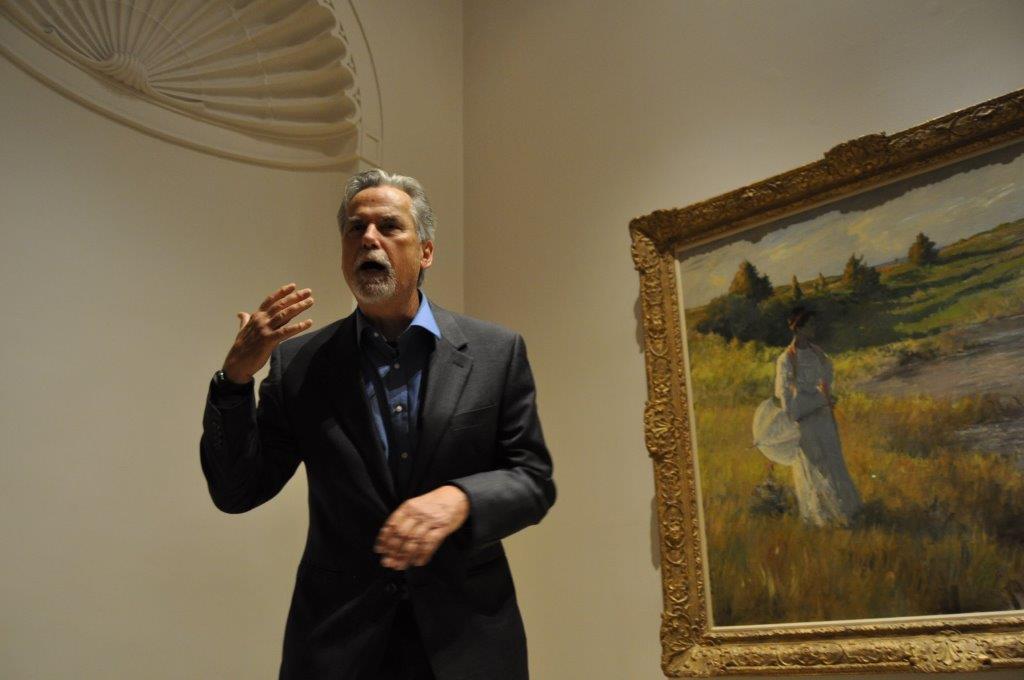 Man speaking in front of a painting in an art museum