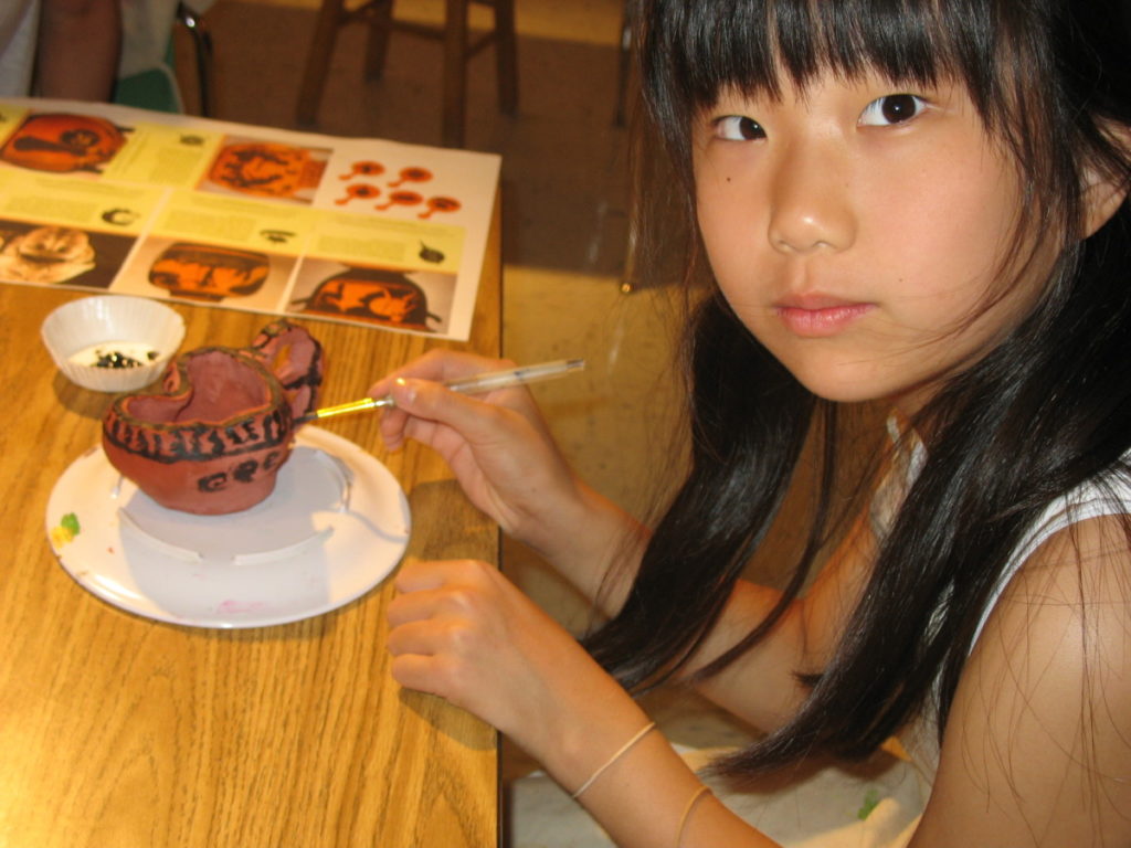 girl painting handmade vessel
