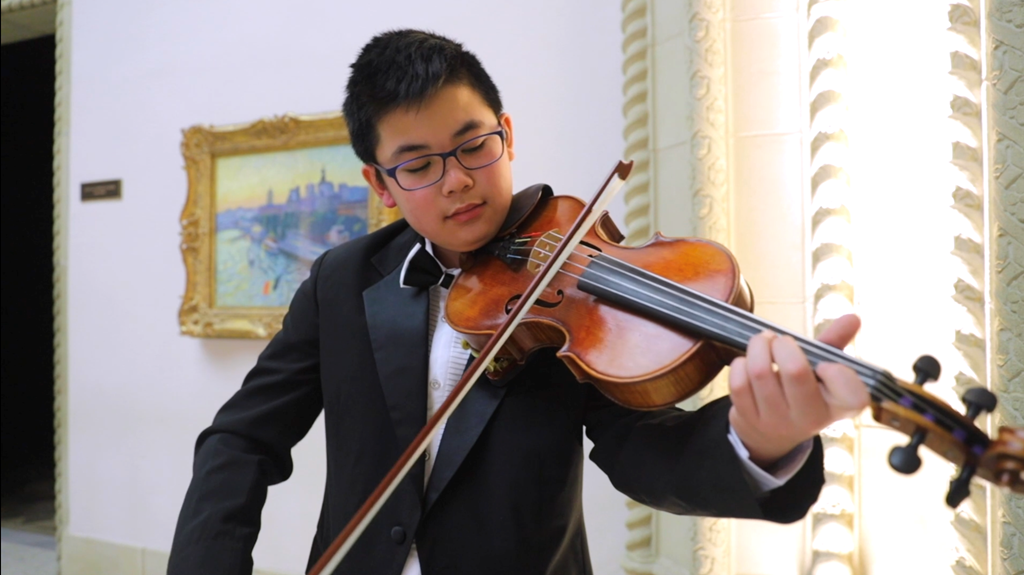 youth playing violin inside museum galleries