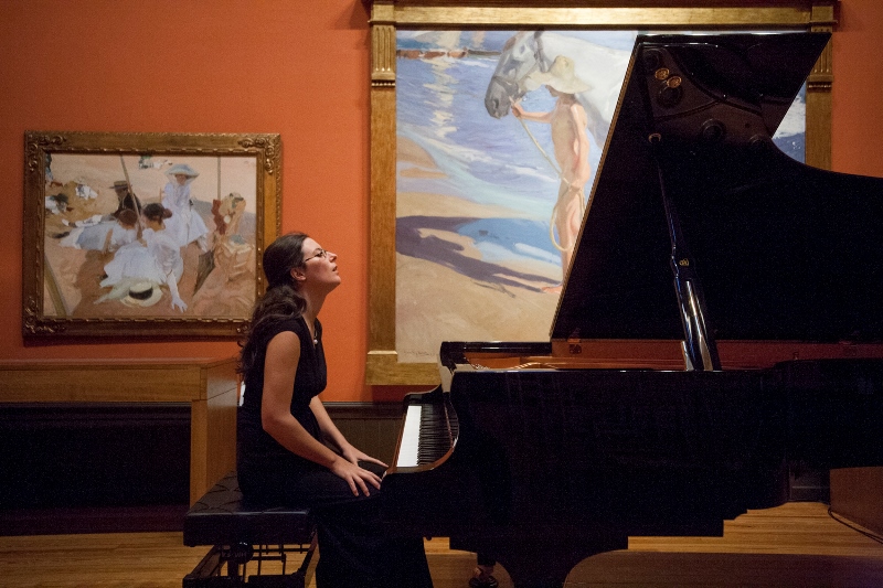 Woman sitting at grand piano inside art museum