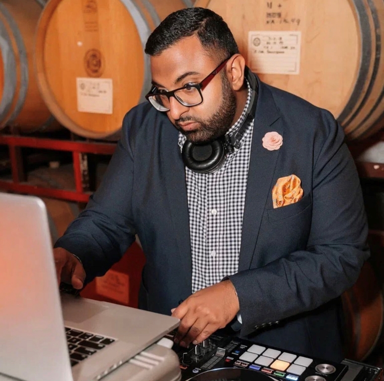 DJ Pratik mixing music with wine barrels in background
