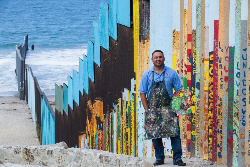 Artist Enrique Chiu with border mural