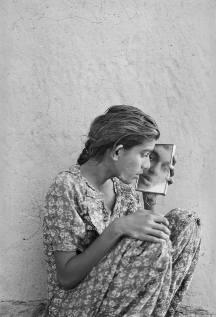 Black and white photo of woman looking at self in mirror