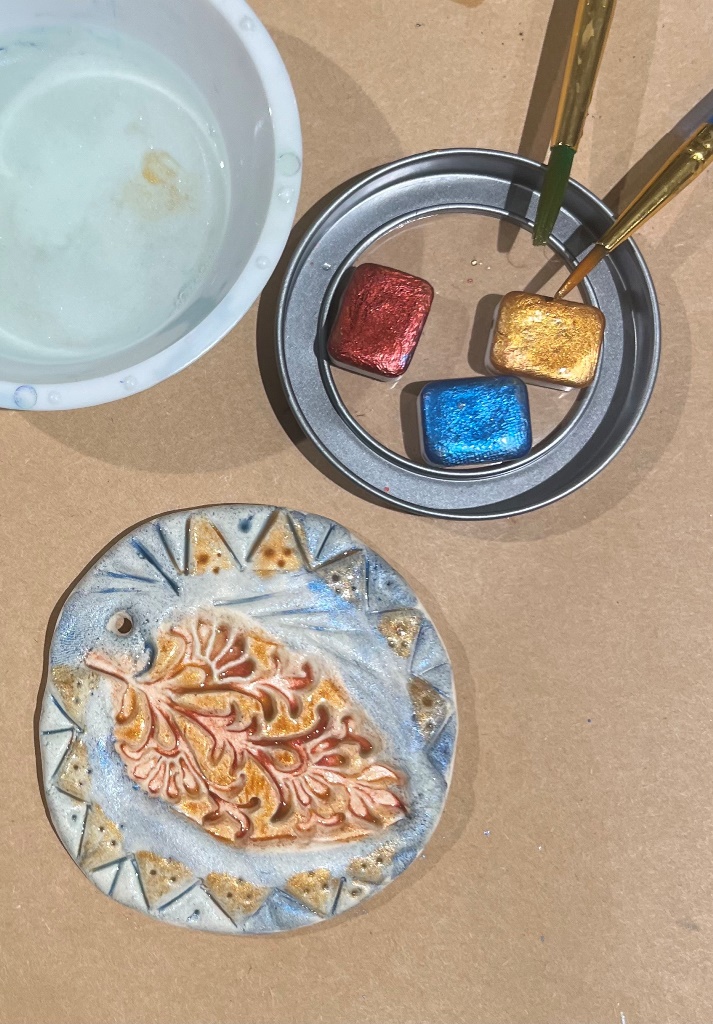 Painted clay round with metallic paint, brushes, and water