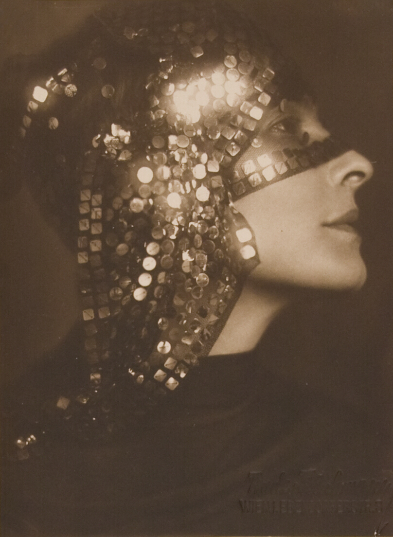Woman in profile with sequined scarf over her head and eyes