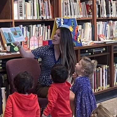 Woman reading to group of young children in library