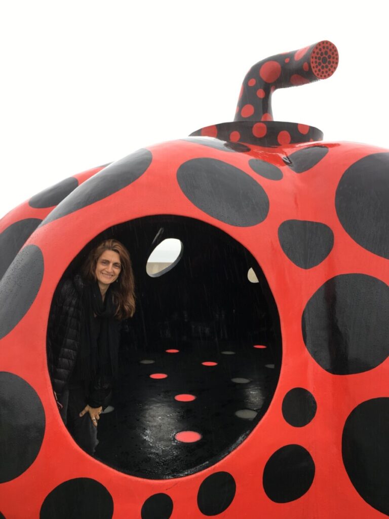 Woman inside pumpkin-shaped sculpture painted red with black polka dots