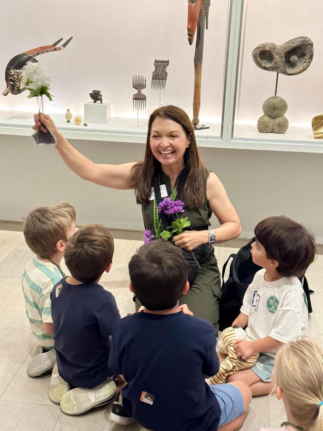 Docent smiling and leading Family Art Adventures Tour with group of young kids